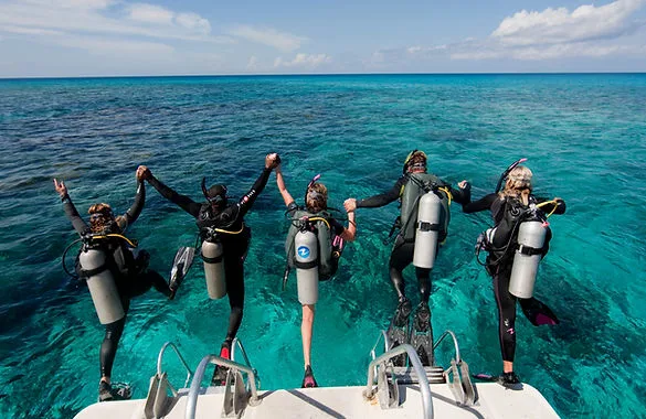 Plongeurs équipés se préparent à sauter d'un bateau en mer turquoise