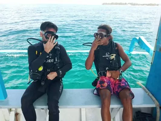 Deux plongeurs équipés se préparent sur un bateau en mer