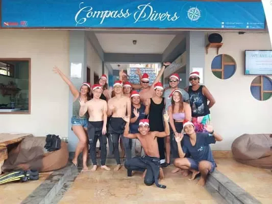 Groupe de personnes souriantes portant des bonnets de Noël devant un centre