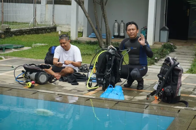 Deux plongeurs équipés près d'une piscine, préparation plongée formation