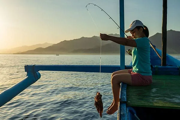 Jeune femme pêchant un poisson depuis un ponton en mer