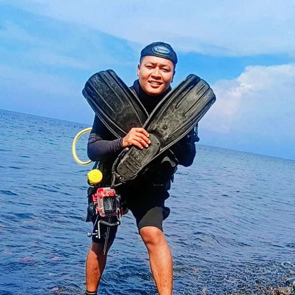 Plongeur souriant sortant de l'eau avec son équipement complet