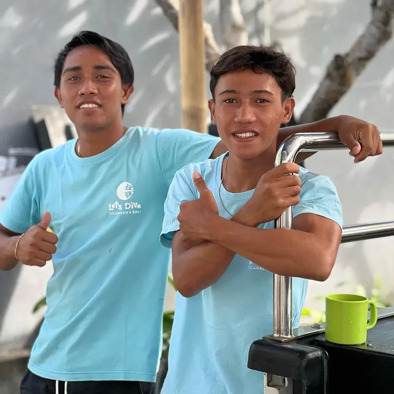 Deux hommes souriants en t-shirt bleu, pouce levé, ambiance détendue