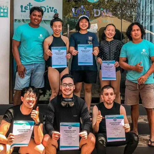 Groupe de plongeurs souriants tenant leurs certificats devant le centre