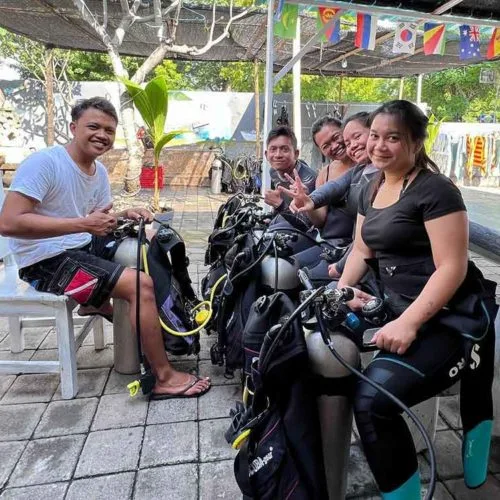 Groupe de plongeurs souriants avec leur équipement complet avant une sortie