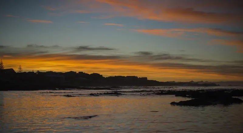Coucher de soleil sur la mer avec bâtiments et rochers silhouettes