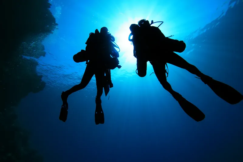 Deux plongeurs en silhouette explorent les profondeurs bleues de l'océan
