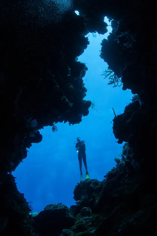 Plongeur solitaire explorant une grotte sous-marine éclairée par le soleil