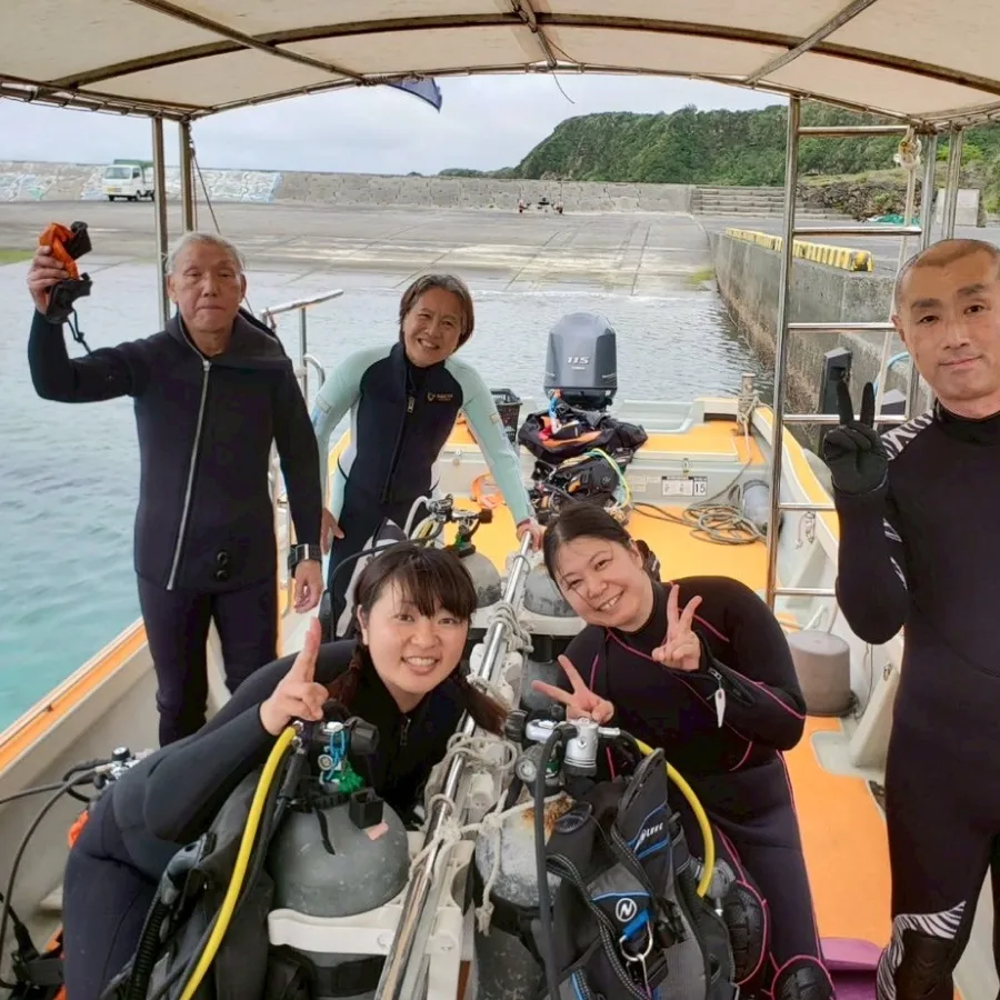 Groupe de plongeurs souriants à bord d'un bateau orange en mer