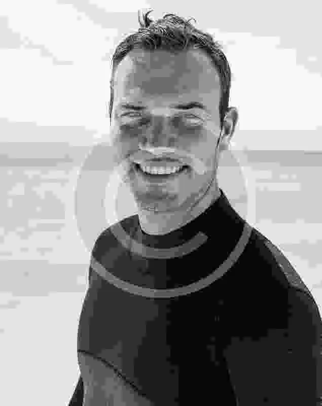 Portrait d'un homme souriant portant une combinaison de plongée noire