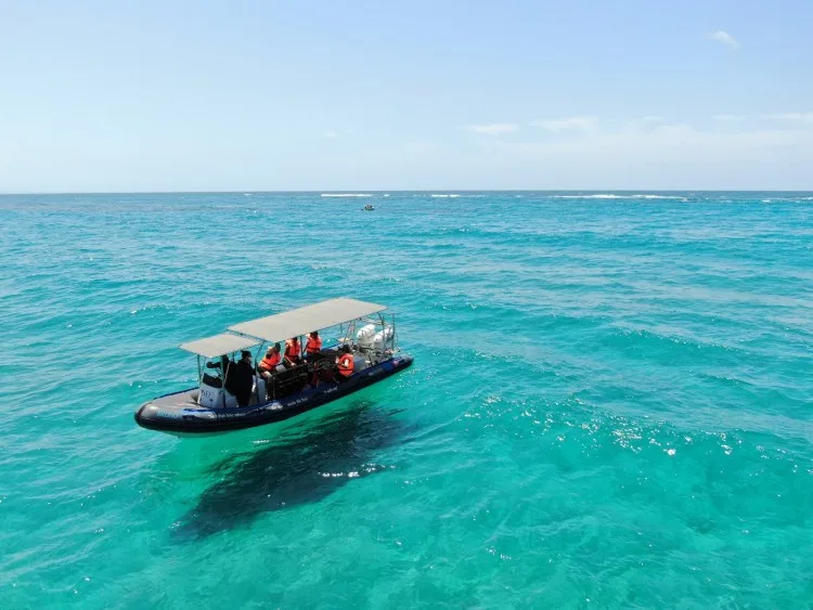 Bateau pneumatique avec passagers naviguant sur une mer turquoise claire