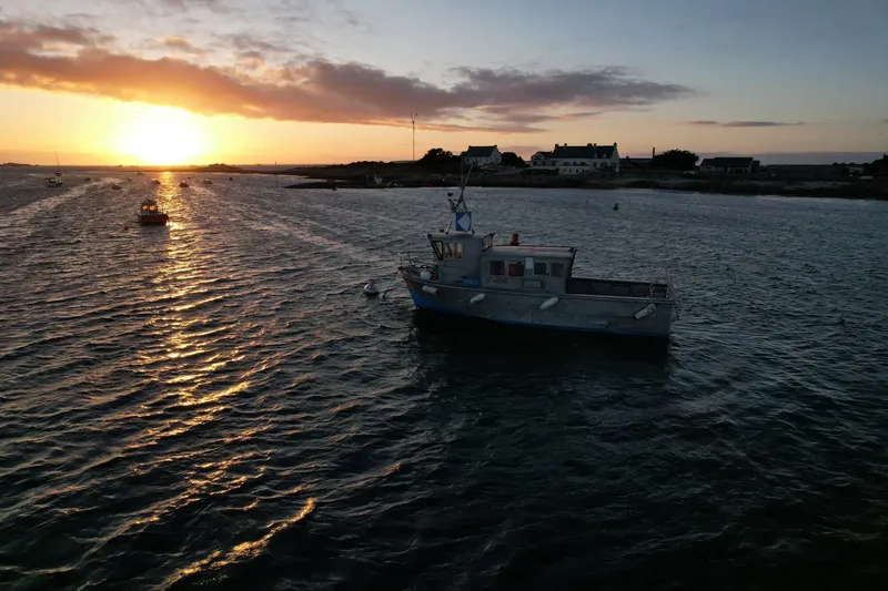 Bateau de pêche au coucher du soleil sur une mer calme