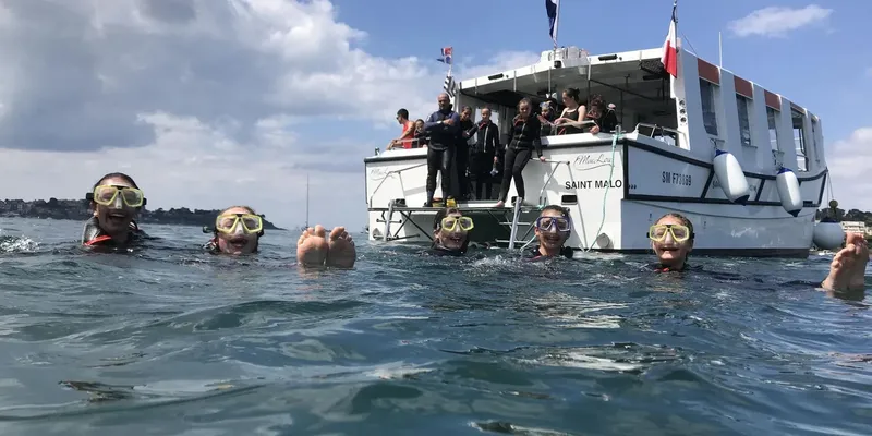 Plongueurs avec masques et tubas nagent près d'un bateau blanc