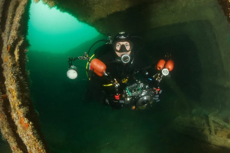 Plongeur équipé explore l'intérieur d'une épave sous-marine éclairée