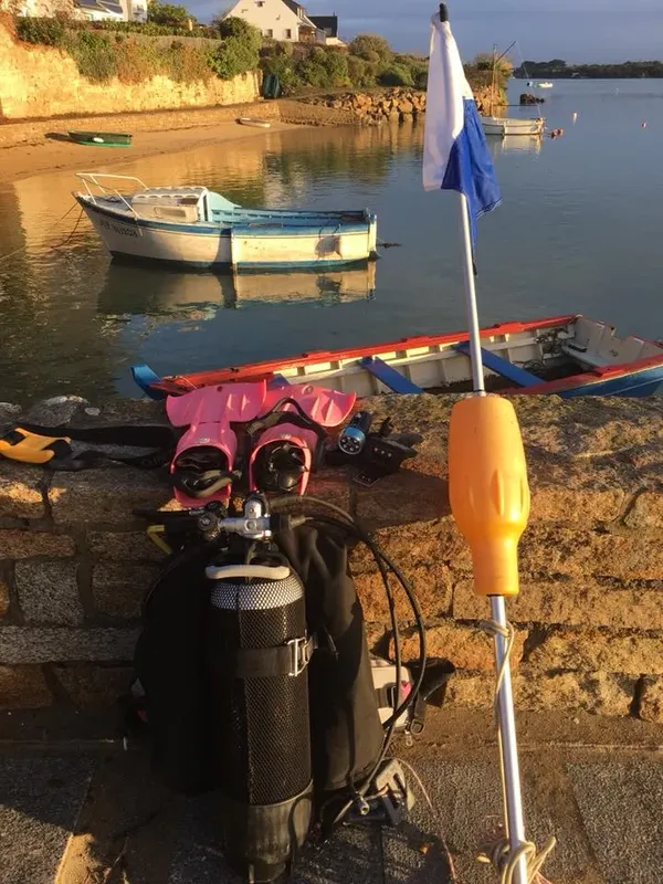 Equipement de plongée sur un quai avec bateaux amarrés au loin