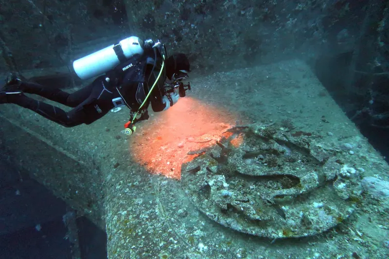 Plongeur explorant une épave sous-marine avec une lumière artificielle