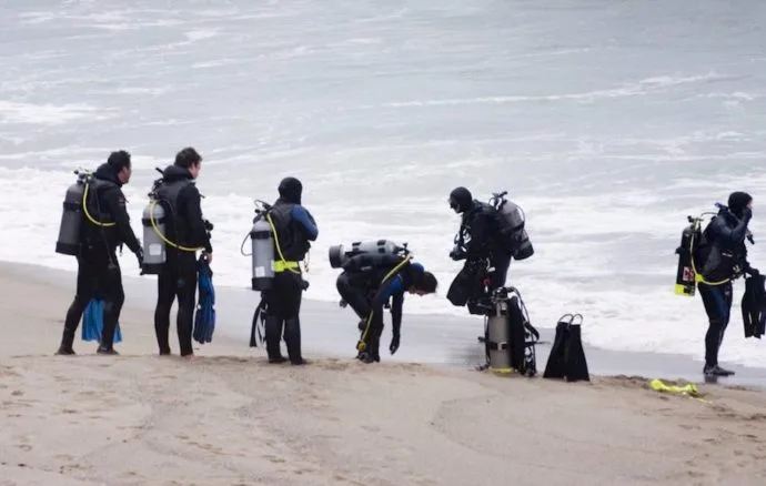 Plongée : groupe de personnes s'équipant sur une plage venteuse