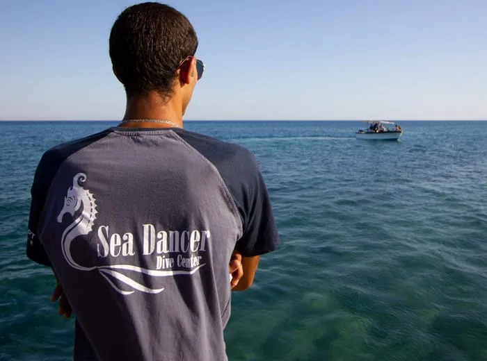 Homme regardant la mer avec un bateau au loin et un t-shirt