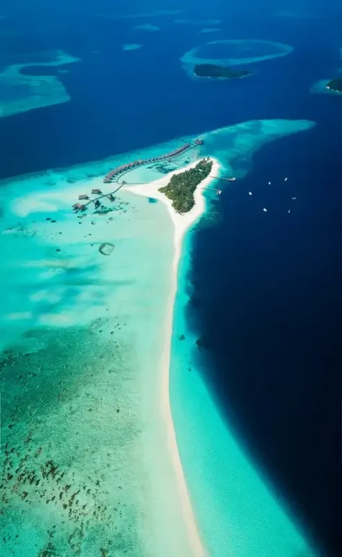 Vue aérienne d'une île tropicale avec lagon turquoise et bateaux