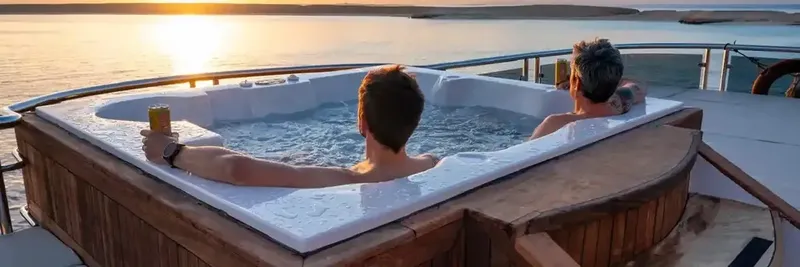 Deux personnes se détendent dans un jacuzzi sur un bateau au coucher du soleil