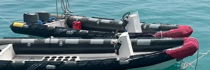 Deux bateaux semi-rigides noirs et gris amarrés sur une mer calme