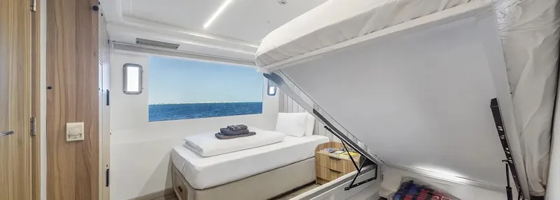Intérieur de cabine de bateau avec lit, fenêtre sur mer et rangement