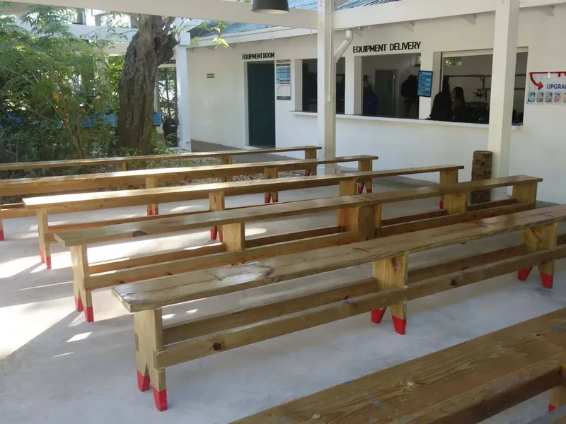 Bancs en bois devant un bâtiment blanc avec des fenêtres ouvertes