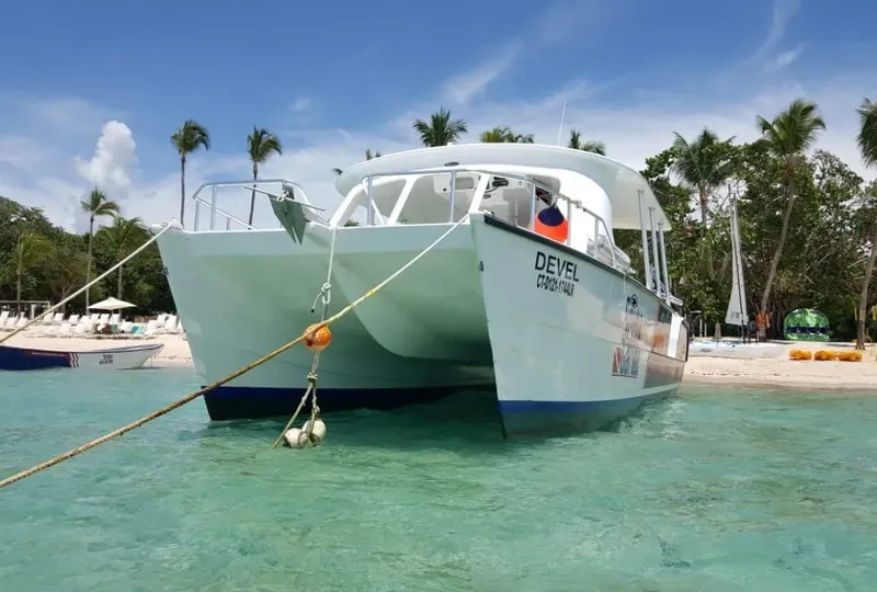 Catamaran amarré dans une eau turquoise avec une plage en arrière-plan