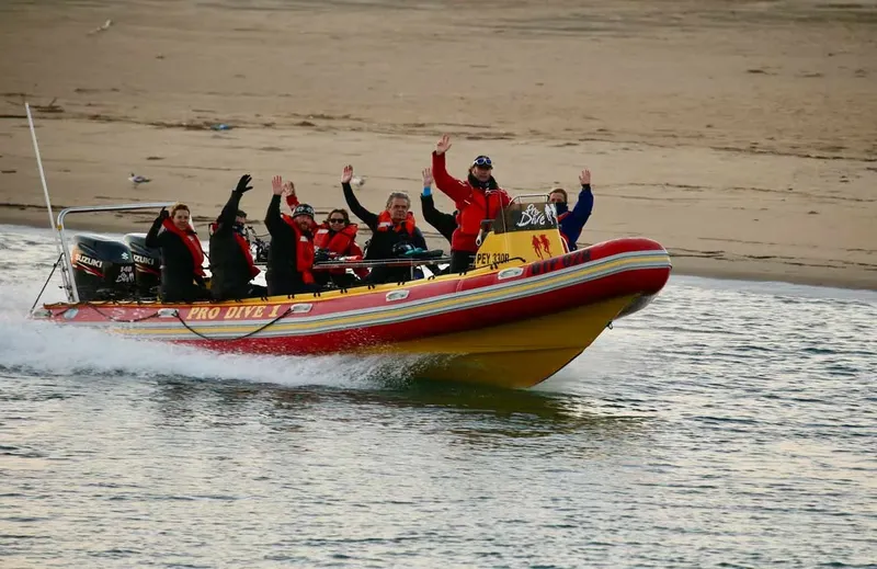 Groupe de personnes sur un bateau semi-rigide en mer levant les bras