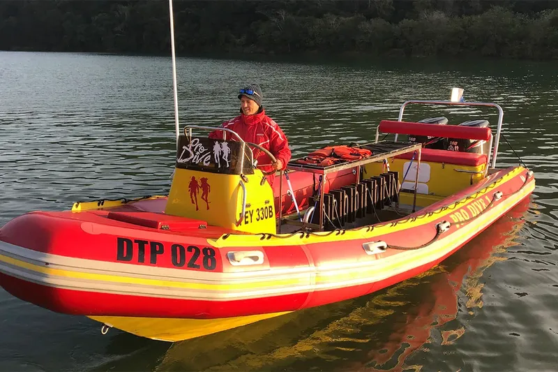 Bateau de plongée rouge et jaune avec un plongeur à bord sur l'eau