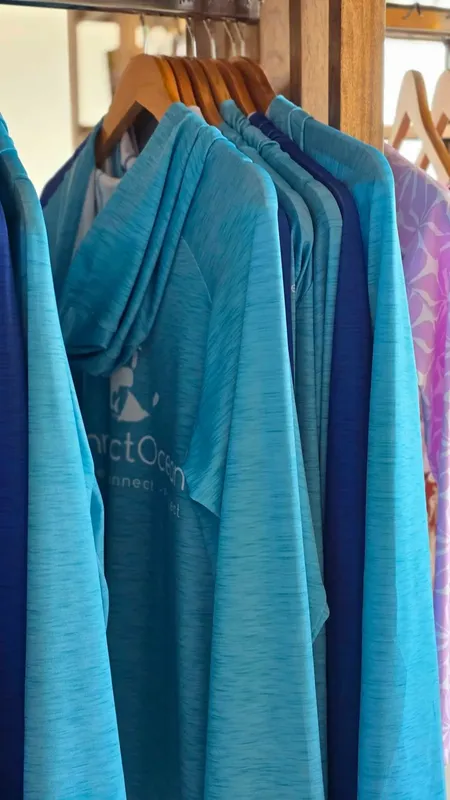 Rangée de vêtements de protection solaire turquoise et bleu suspendus sur cintres