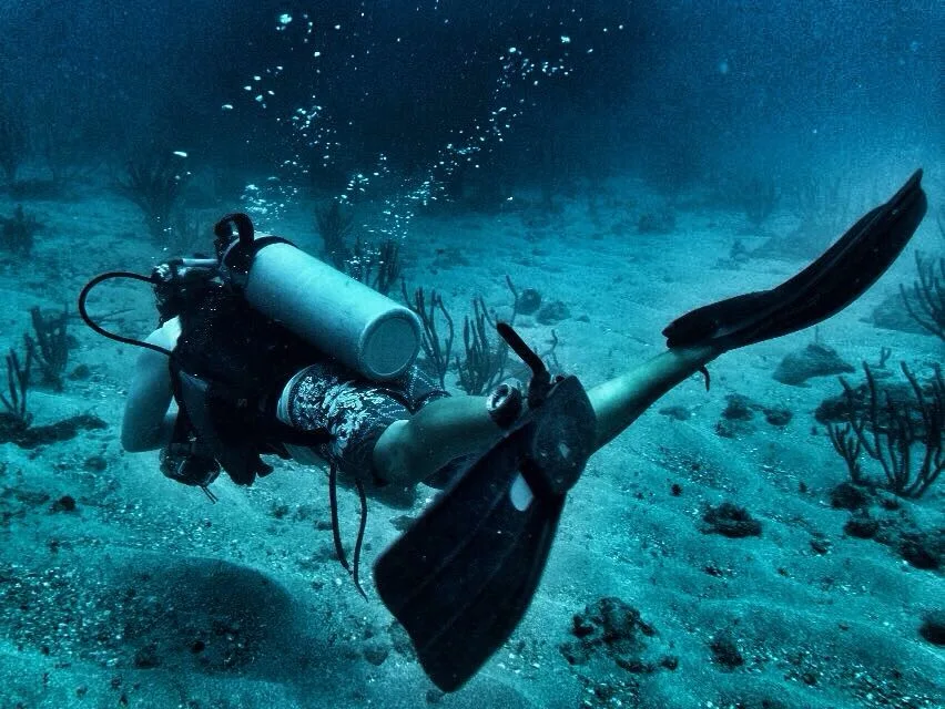 Plongeur en mouvement dans un environnement sous-marin bleu et sablonneux