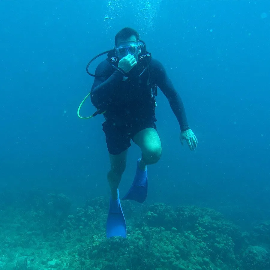 Plongeur en combinaison nageant dans une eau bleue claire et limpide