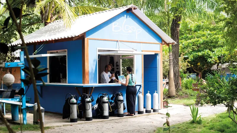 Petit bâtiment bleu avec des bouteilles de plongée et deux personnes