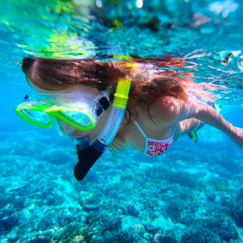 Femme nageant en apnée, vue sous-marine, eau turquoise et récif corallien