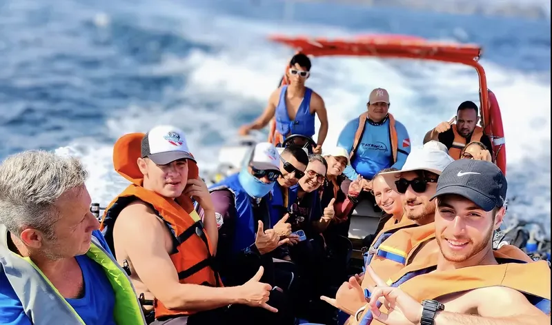 Groupe de personnes souriantes à bord d'un bateau de plongée en mer