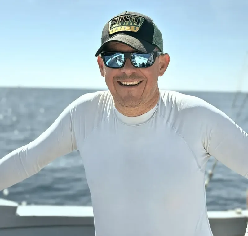 Homme souriant portant un t-shirt et une casquette sur un bateau