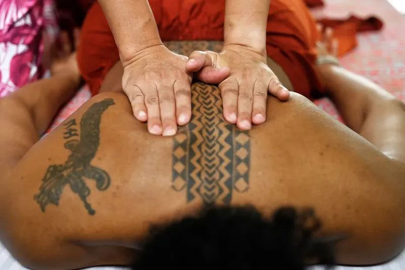 Massage traditionnel polynésien sur le dos d'un homme tatoué
