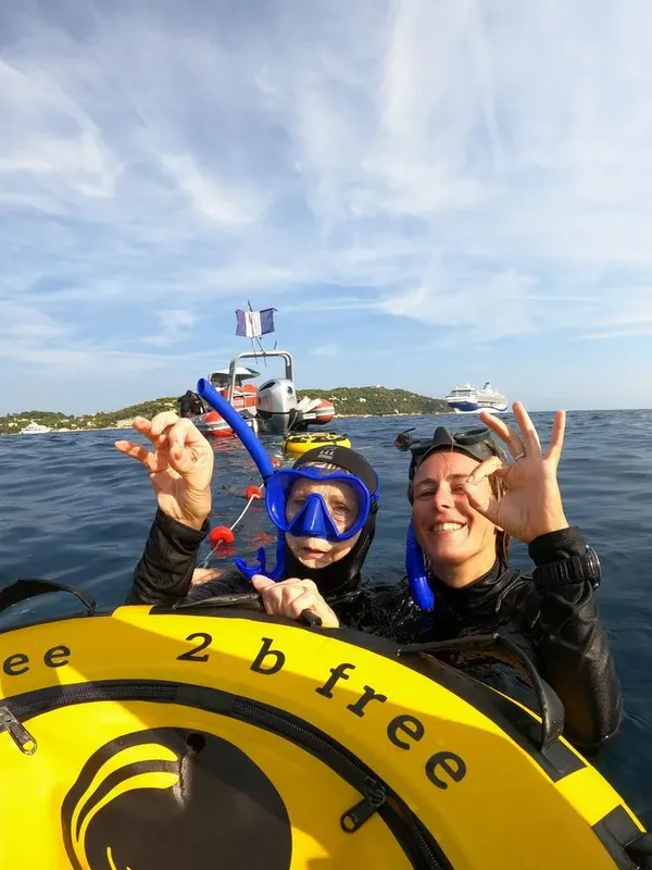 Deux plongeuses souriantes avec tuba en mer, bateau en arrière-plan