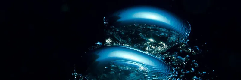 Deux bulles bleues s'élèvent dans l'obscurité de l'eau profonde