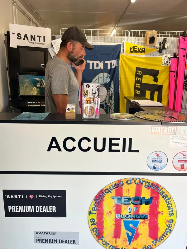 Stand de plongée avec un homme regardant du matériel et des logos