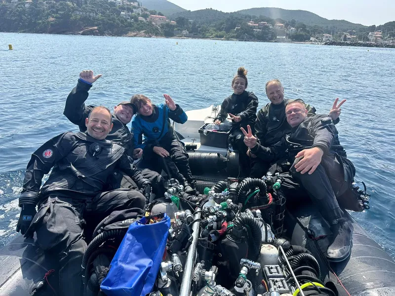 Groupe de plongeurs souriants à bord d'un bateau semi-rigide en mer