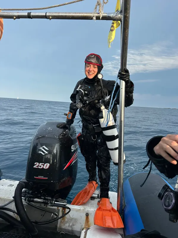 Plongeuse souriante en combinaison complète sur un bateau de plongée