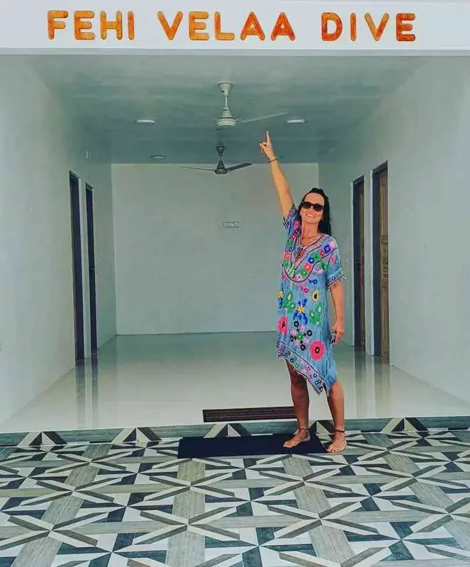 Femme souriante dans un couloir décoré, levant le bras en signe de joie