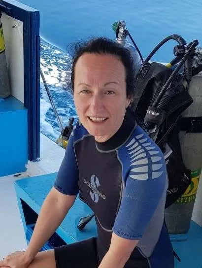 Plongeuse souriante en combinaison, équipée, sur un bateau de plongée