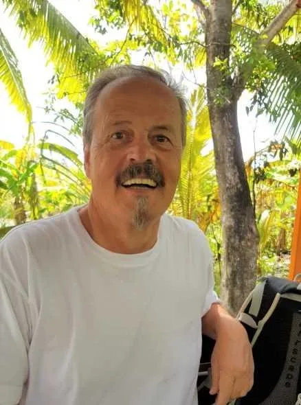 Homme souriant avec un sac de plongée sur l'épaule végétation