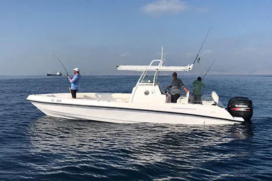 Trois personnes pêchant sur un bateau blanc en pleine mer