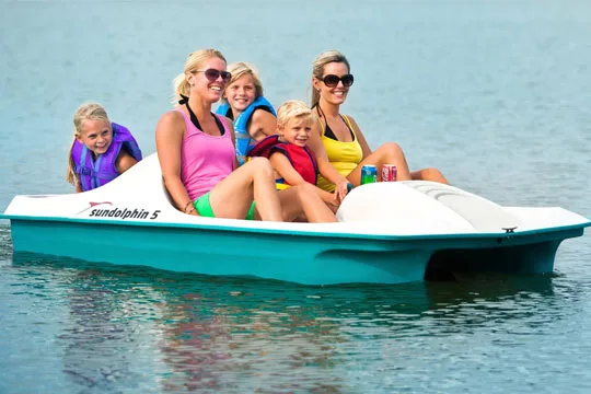 Famille souriante sur un pédalo turquoise en pleine mer ensoleillée