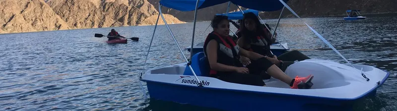 Personnes sur pédalo bleu en mer, montagnes en arrière-plan