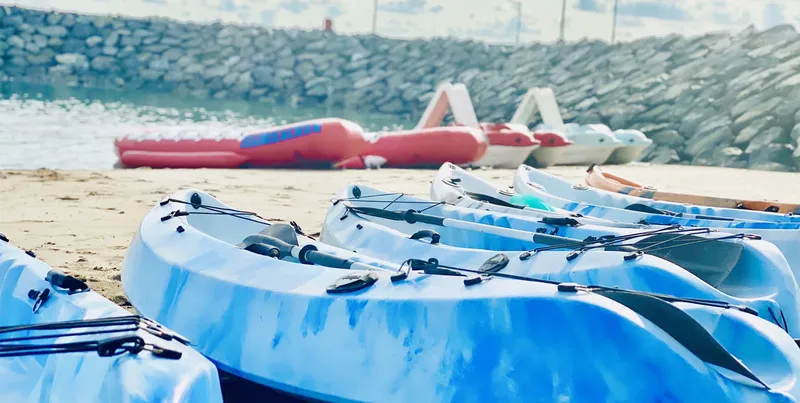 Kayaks bleus et blancs alignés sur une plage de sable clair